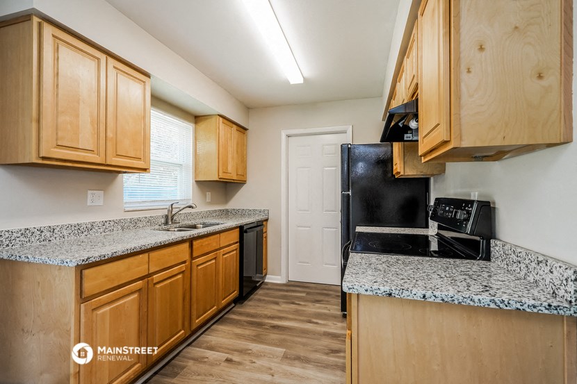 a kitchen with wood cabinets and granite counter tops and a black refrigerator