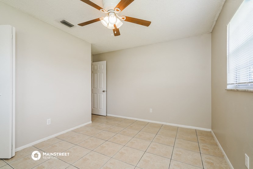 the spacious living room has a ceiling fan and tile flooring