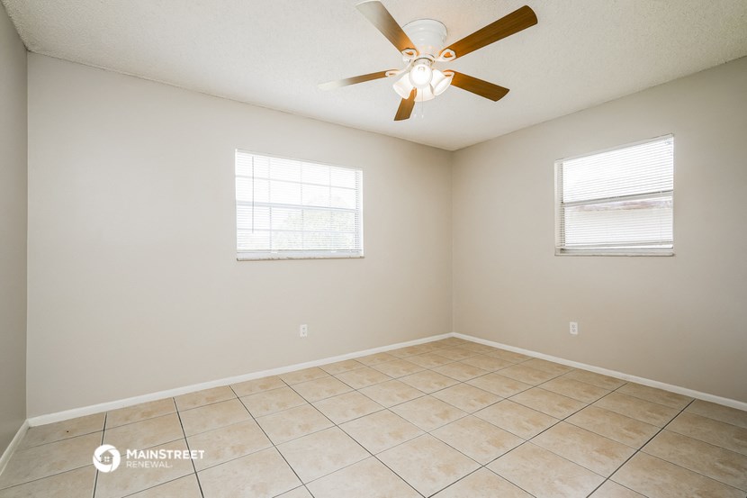 the spacious living room has a ceiling fan and tile flooring