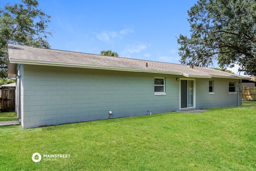 the front of a blue house with a lawn and trees