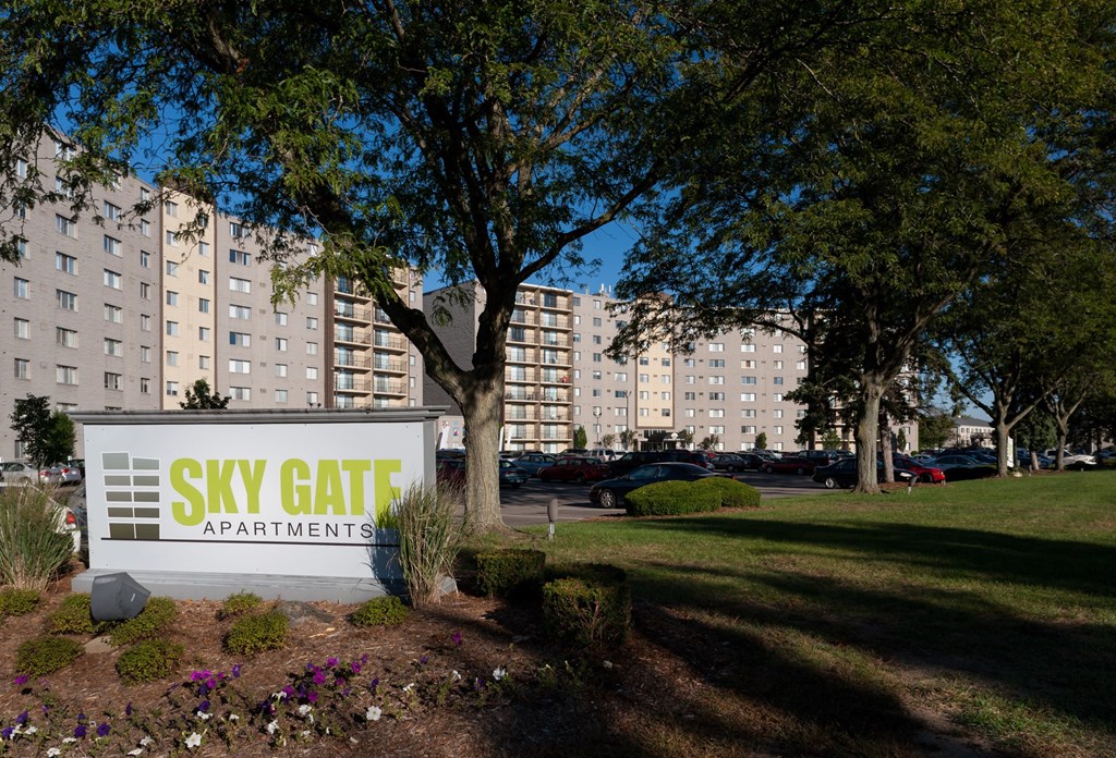 a view of the sky gate apartments sign in front of a park