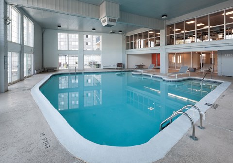 a swimming pool in a building with large windows and a blue pool