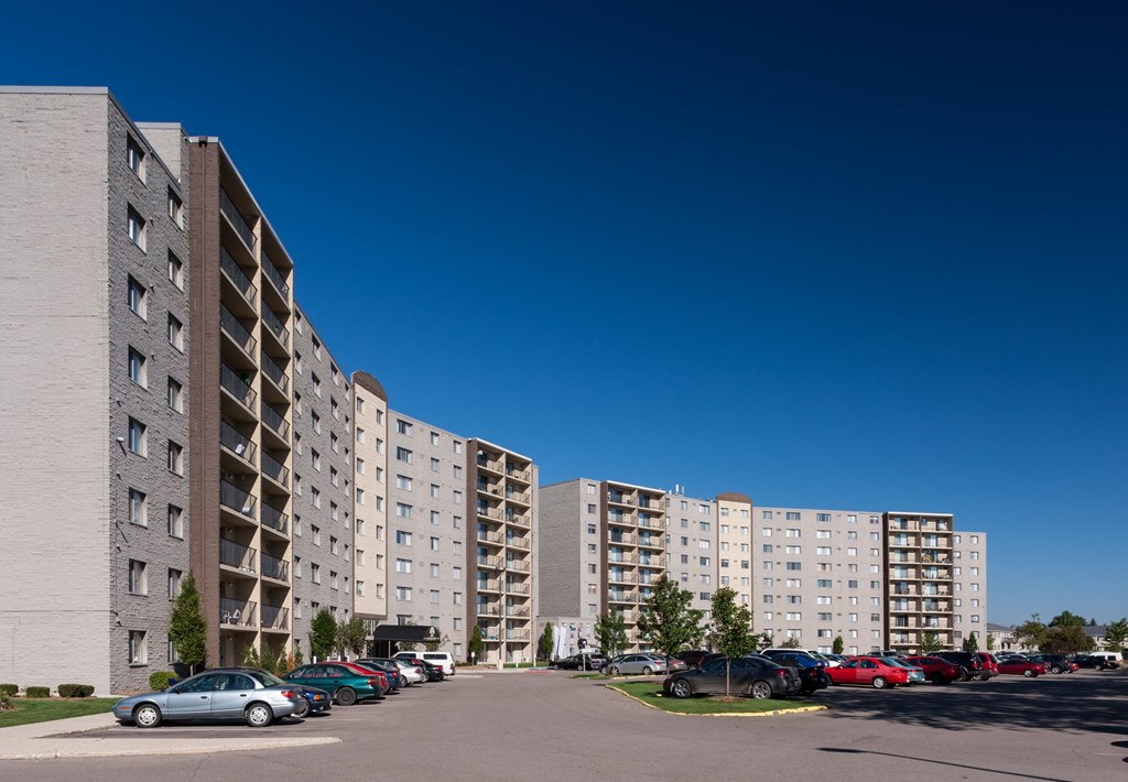 a row of apartment buildings with cars parked in a parking lot