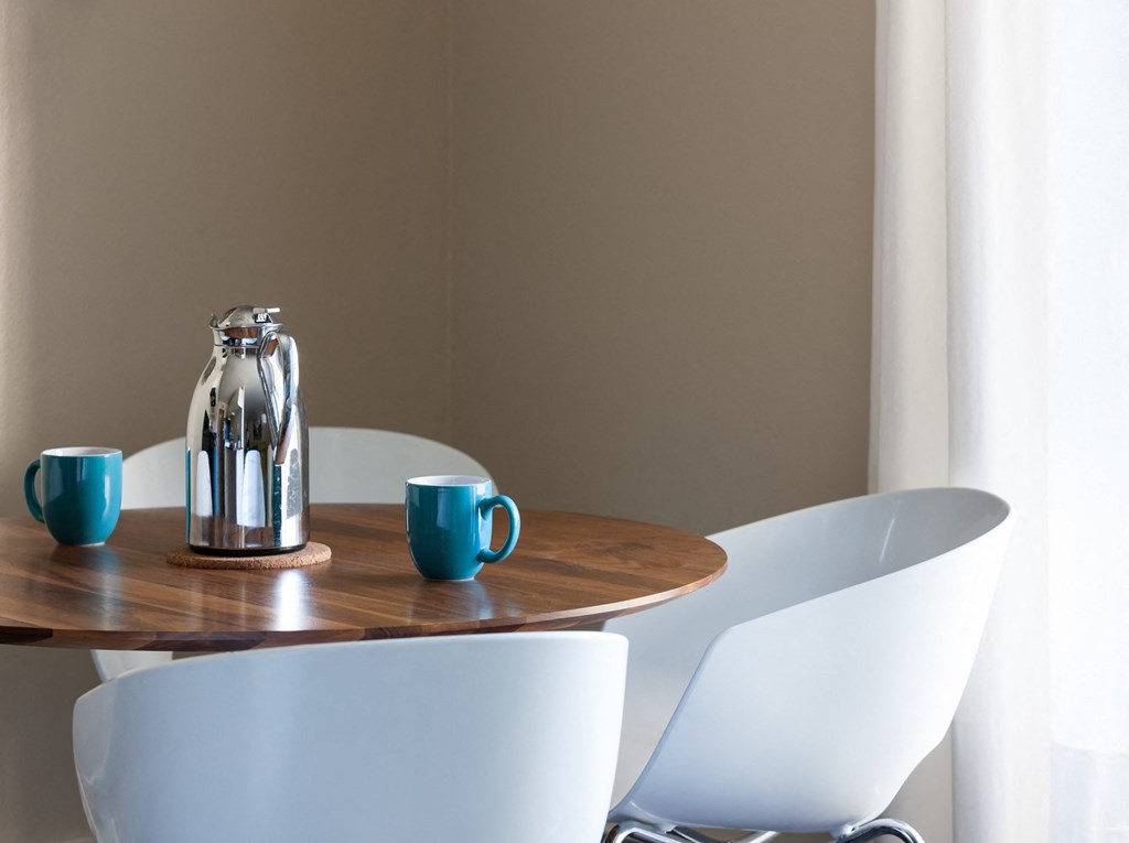 a table with chairs and a pitcher and cups on it