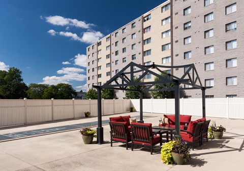 a patio with red chairs and a table under a gazebo