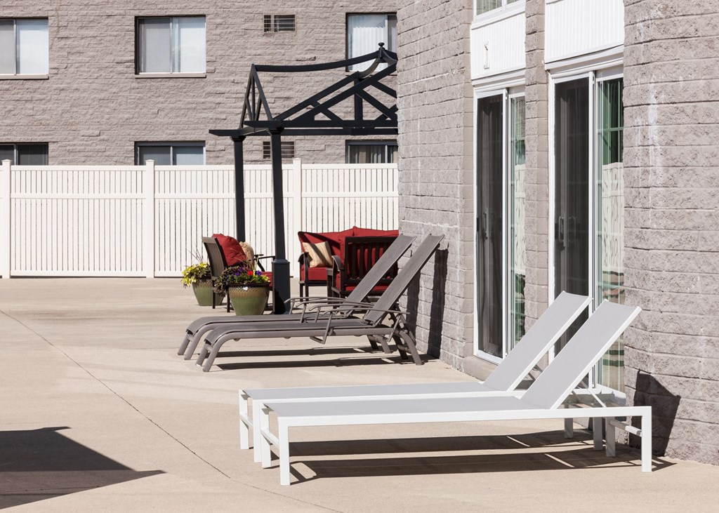 two white lawn chairs on a patio outside of a building