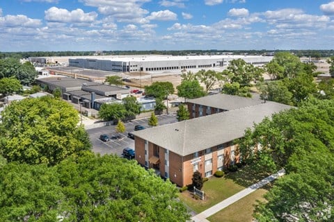 an aerial view of a brick building with trees and a parking lot