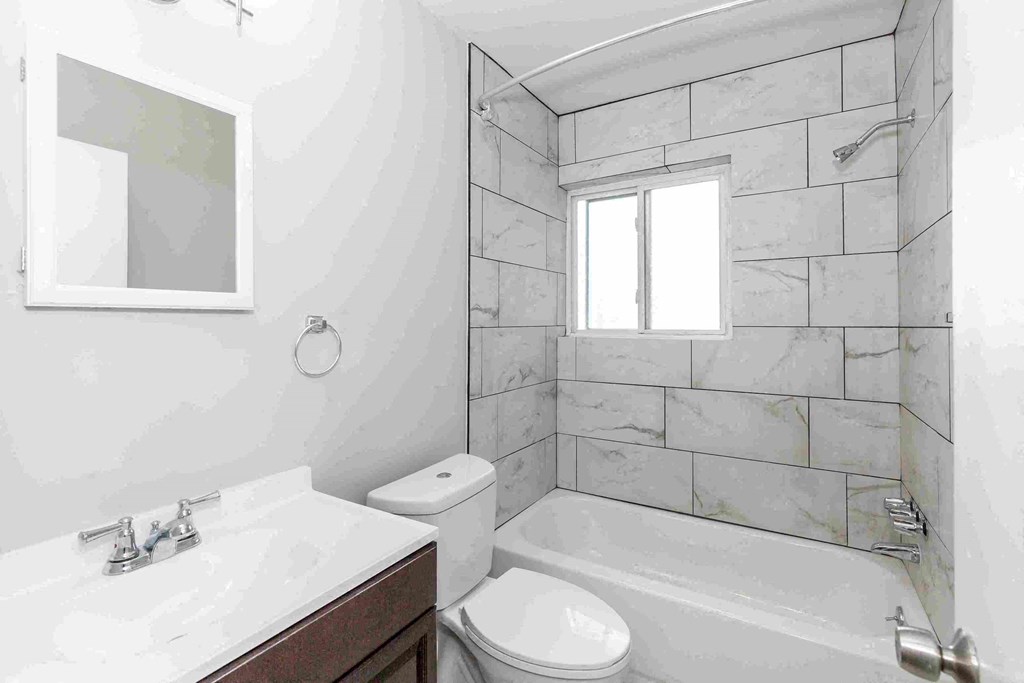 a white bathroom with a tub and a sink and a toilet