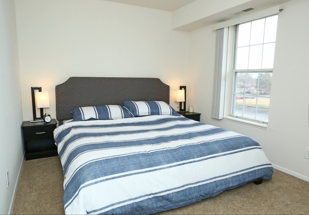 a bedroom with a bed and a large window