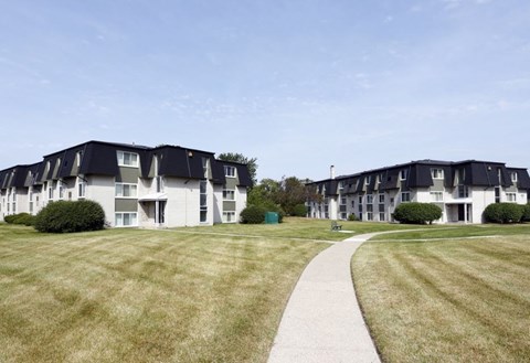 a sidewalk leading to a row of houses on a grass field