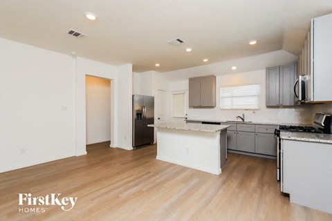 A kitchen with a white counter top and wooden floors.