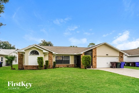 A house with a well-maintained lawn and a clear blue sky above.