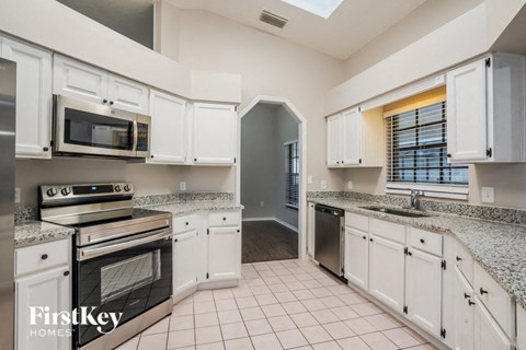 A kitchen with white cabinets and a granite countertop.