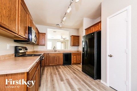A kitchen with wooden cabinets and a black fridge.