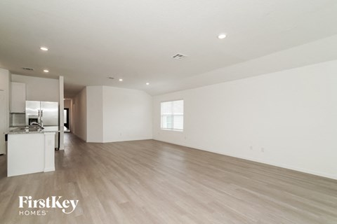 a spacious living room with white walls and wood flooring