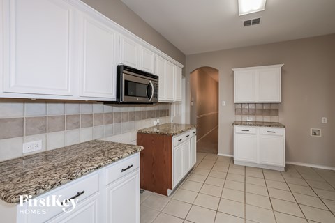 A kitchen with white cabinets and a granite countertop.