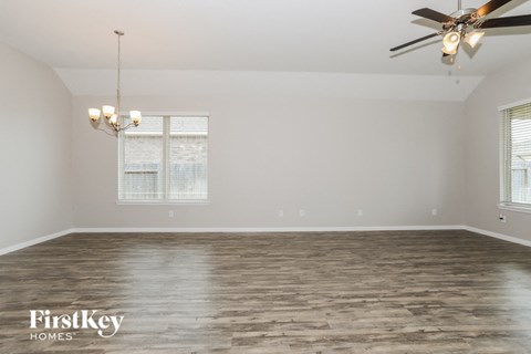 the spacious living room with wood flooring and a ceiling fan