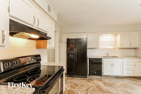 a kitchen with white cabinets and black appliances