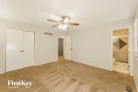 a bedroom with a ceiling fan and a door to a bathroom