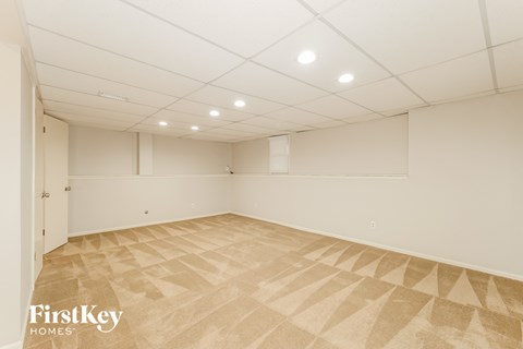 a spacious room with white walls and tile flooring
