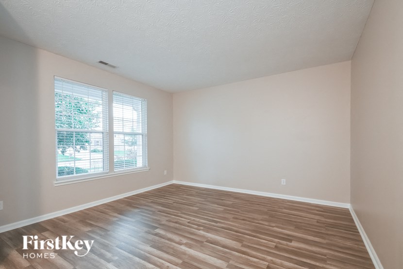 a bedroom with wood floors and white walls and a window