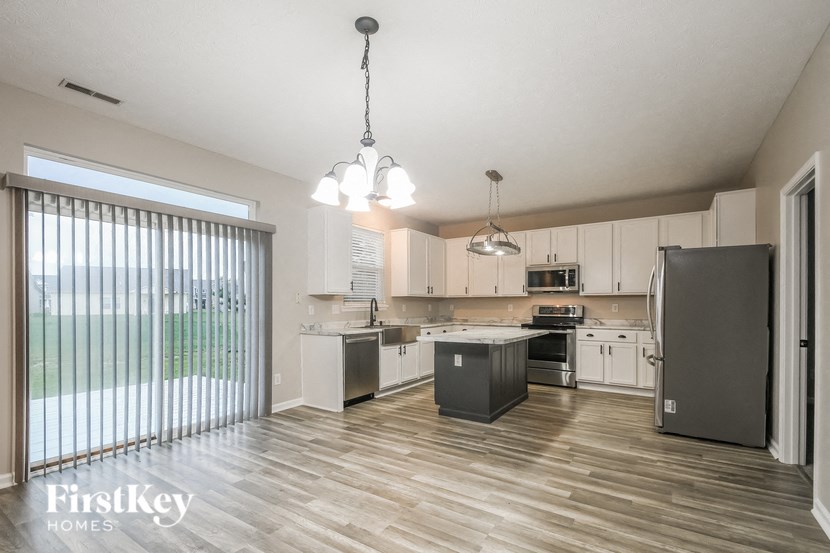 a kitchen with white cabinets and stainless steel appliances and a large window