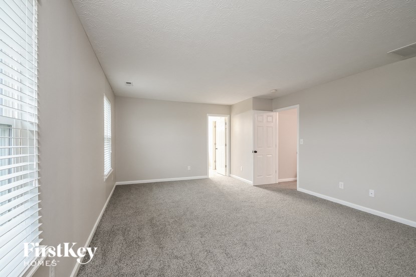 an empty living room with white carpet and a white door