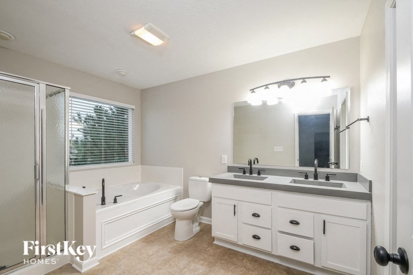 a white bathroom with a tub and a sink and a mirror
