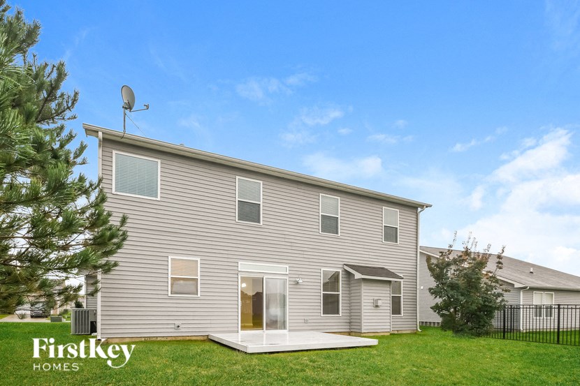 a gray house with a yard and a satellite dish on top of it