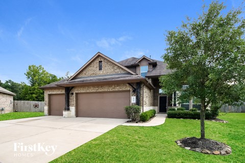 a home with a garage and a tree on the side of the driveway