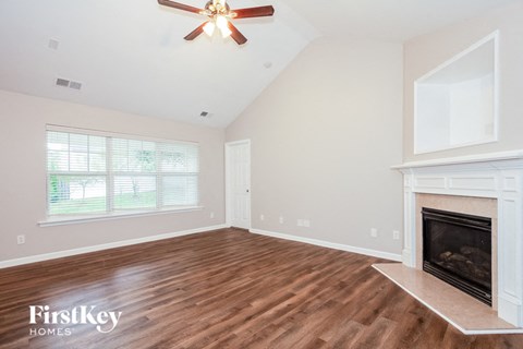 A spacious room with a fireplace and a ceiling fan.