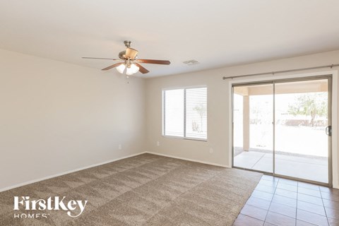 A spacious room with a ceiling fan and sliding glass doors leading to a patio.