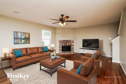 A living room with a brown leather couch and a ceiling fan.