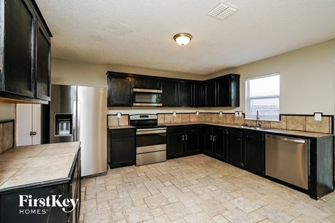 A kitchen with black cabinets and a tile floor.