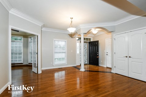an empty living room with a hard wood floor and white doors