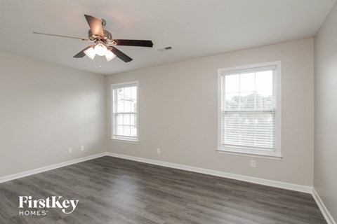 a bedroom with a ceiling fan and two windows