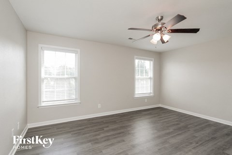 a living room with a ceiling fan and two windows