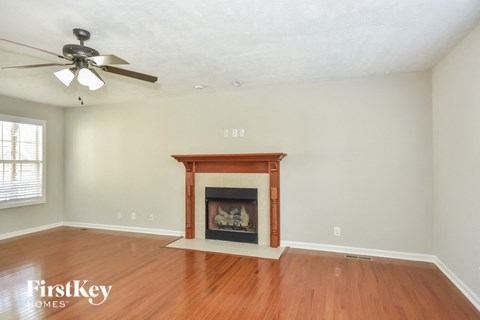 a living room with a fireplace and wooden floors and a ceiling fan