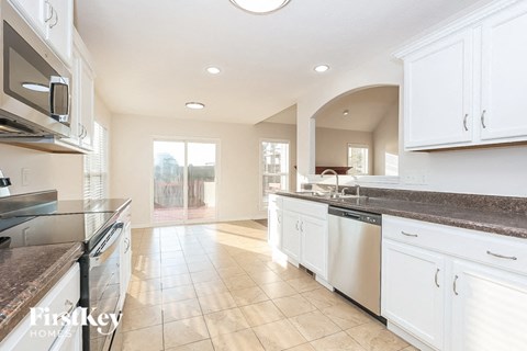 A kitchen with white cabinets and a marble countertop.