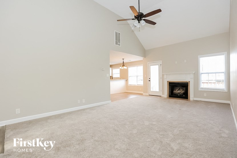 an empty living room with a ceiling fan and a fireplace