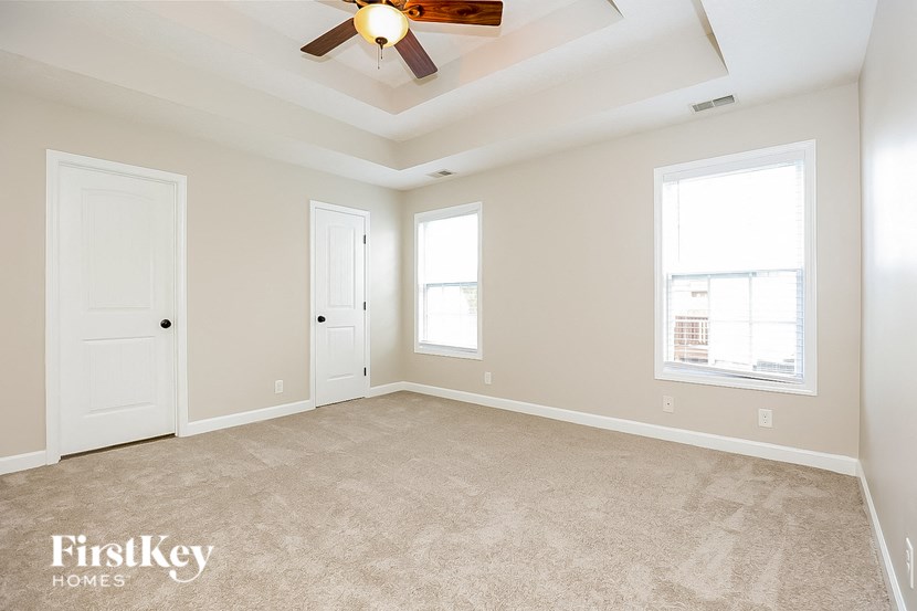 an empty living room with a ceiling fan and two doors