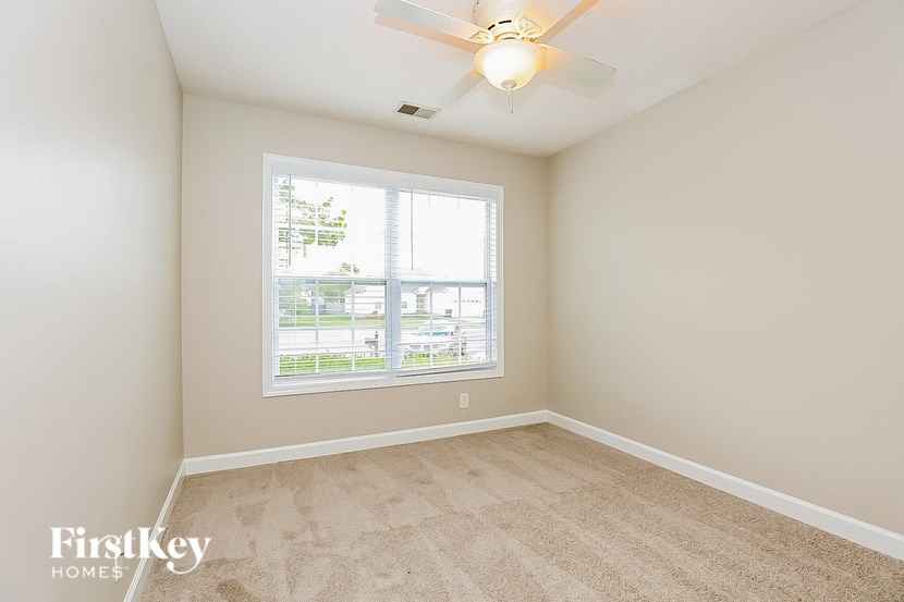 an empty bedroom with a window and a ceiling fan