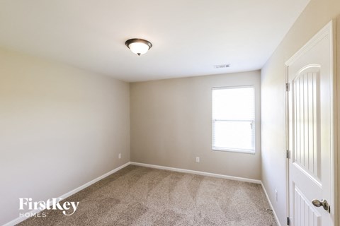 a bedroom with carpet and a white door and a window