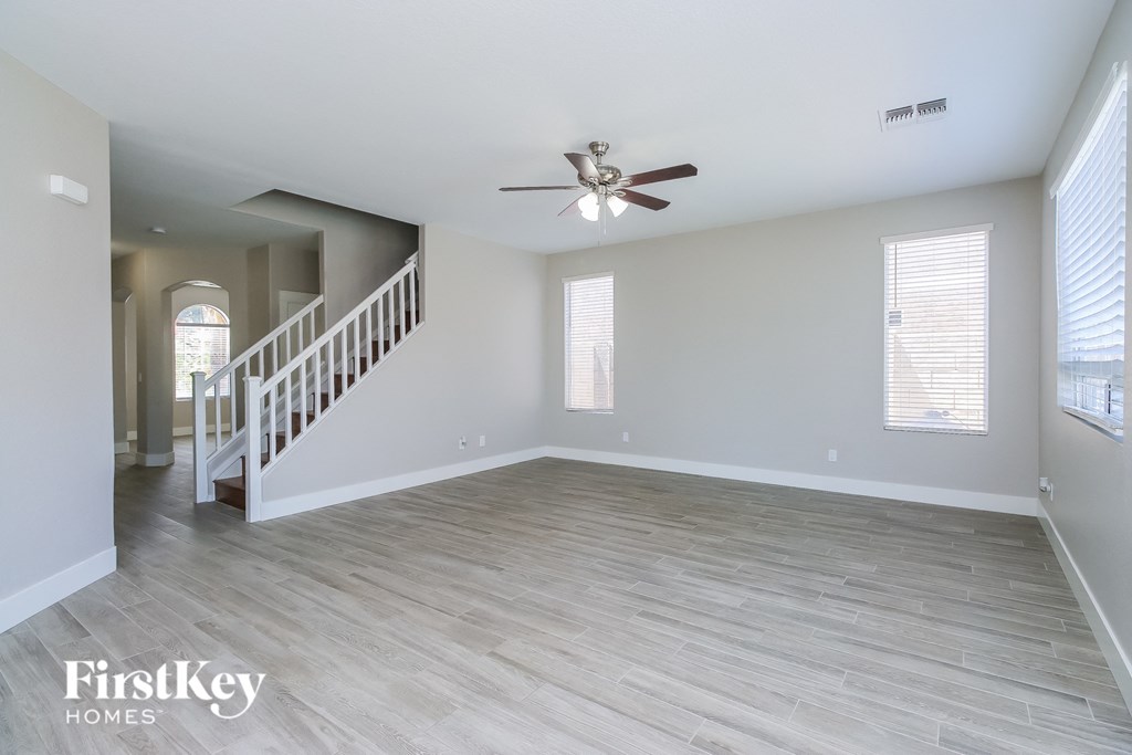 A spacious room with a staircase and a ceiling fan.