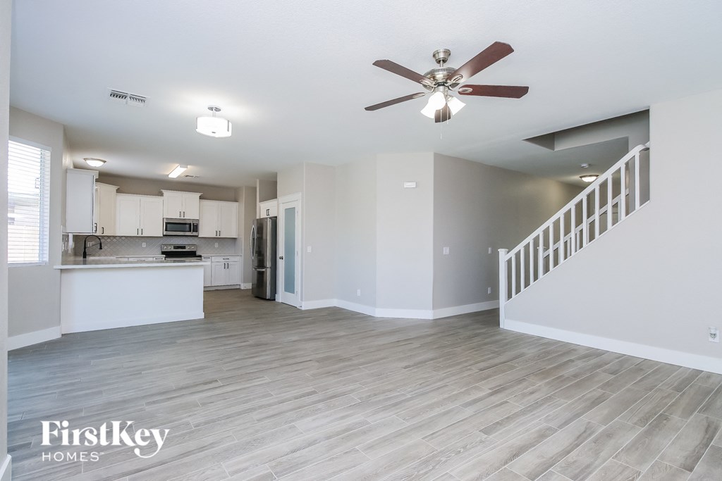 A spacious kitchen and living room with a staircase on the right.