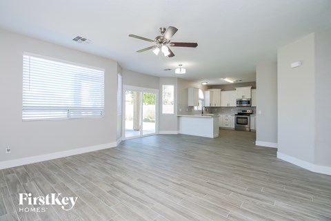 A spacious living room with a ceiling fan and lighting fixture.