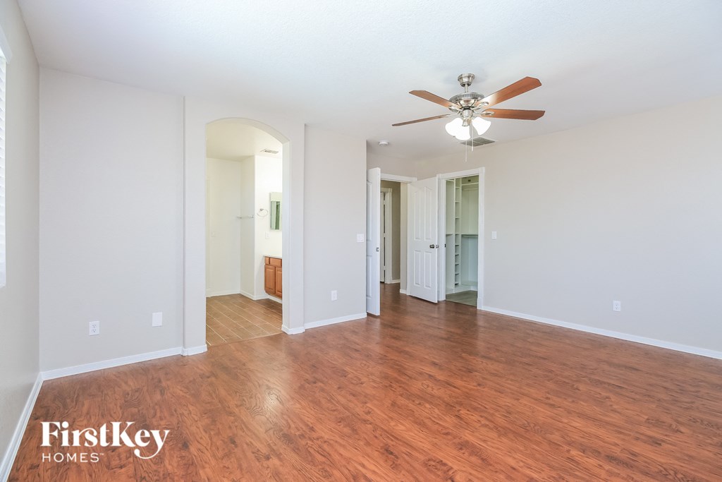 A spacious room with a ceiling fan and wooden flooring.