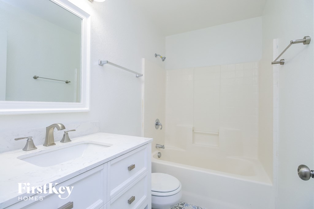 A white bathroom with a toilet, sink, and bathtub.