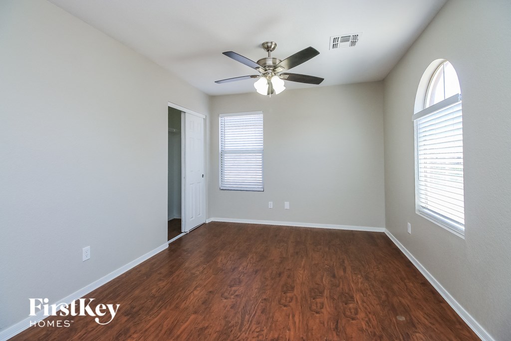 A room with a ceiling fan and wooden flooring.