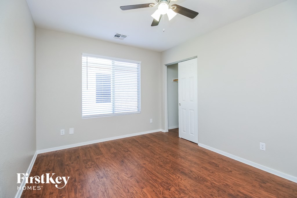 A room with a ceiling fan and wooden flooring.